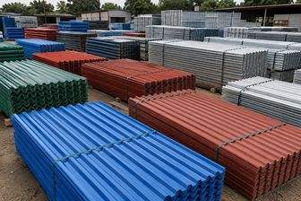 Bundles of colour coated roofing sheet in blue, red and green, with plain galvanised sheet behind
