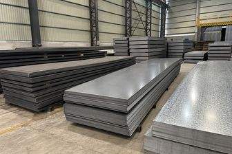 Steel plates stacked flat under a shed roof, with galvanised sheet beside them